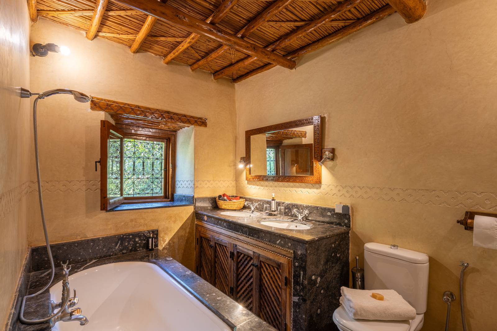 Salle de bains de l'Apartment Suite, baignoire encastrée et double vasque sur plan de marbre sombre
