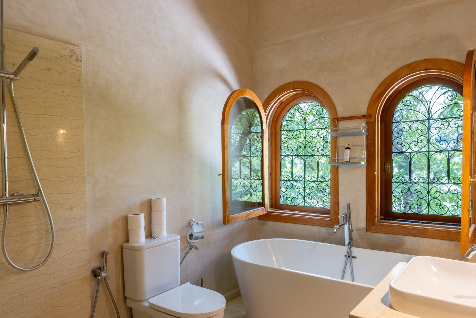 Salle de bains Deluxe Plus : baignoire îlot sous trois fenêtres en arc à grilles de fer forgé, douche séparée