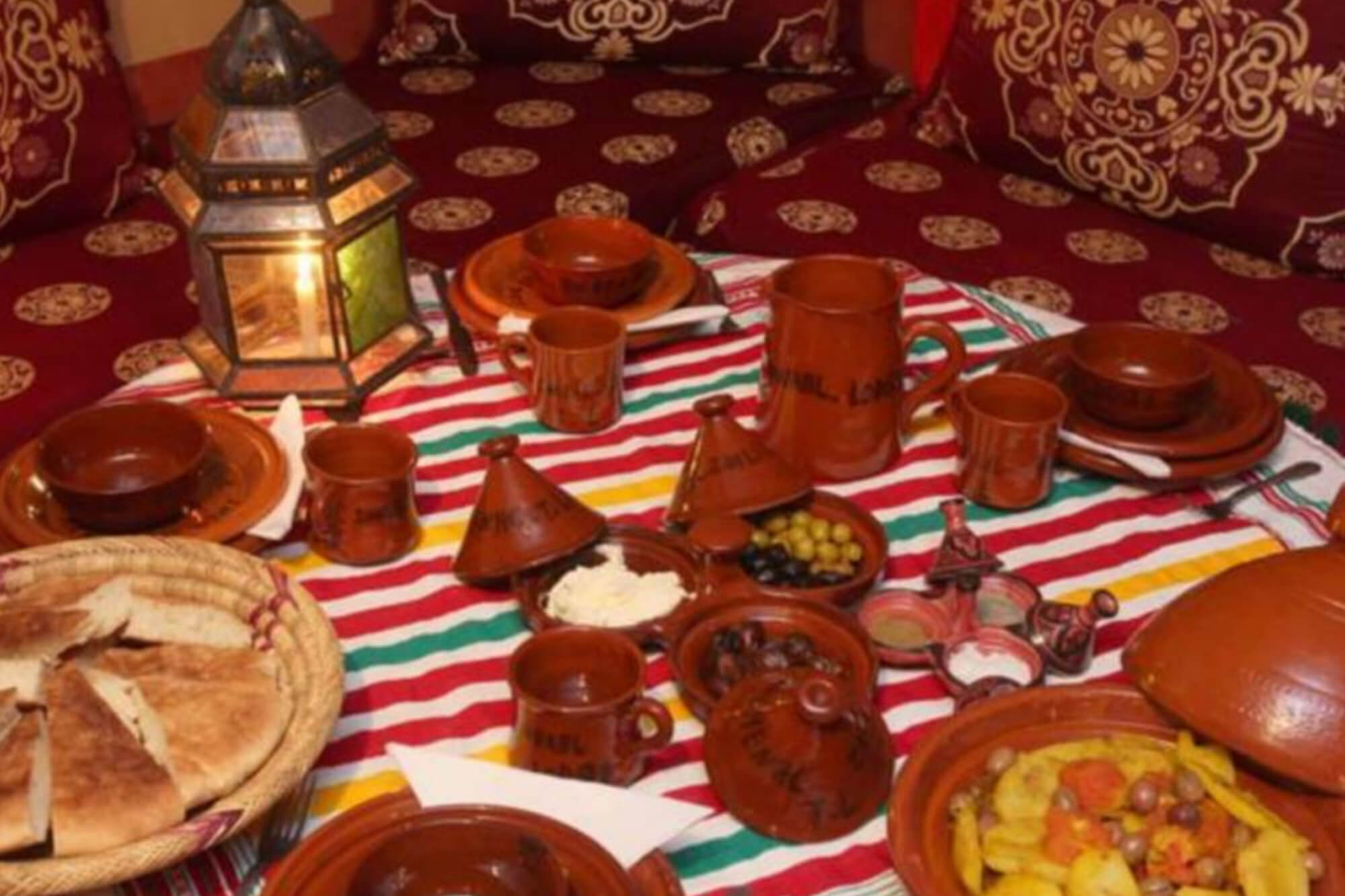 Table du dîner avec tagines, pain, olives et vaisselle en terre cuite marquée au nom du lodge