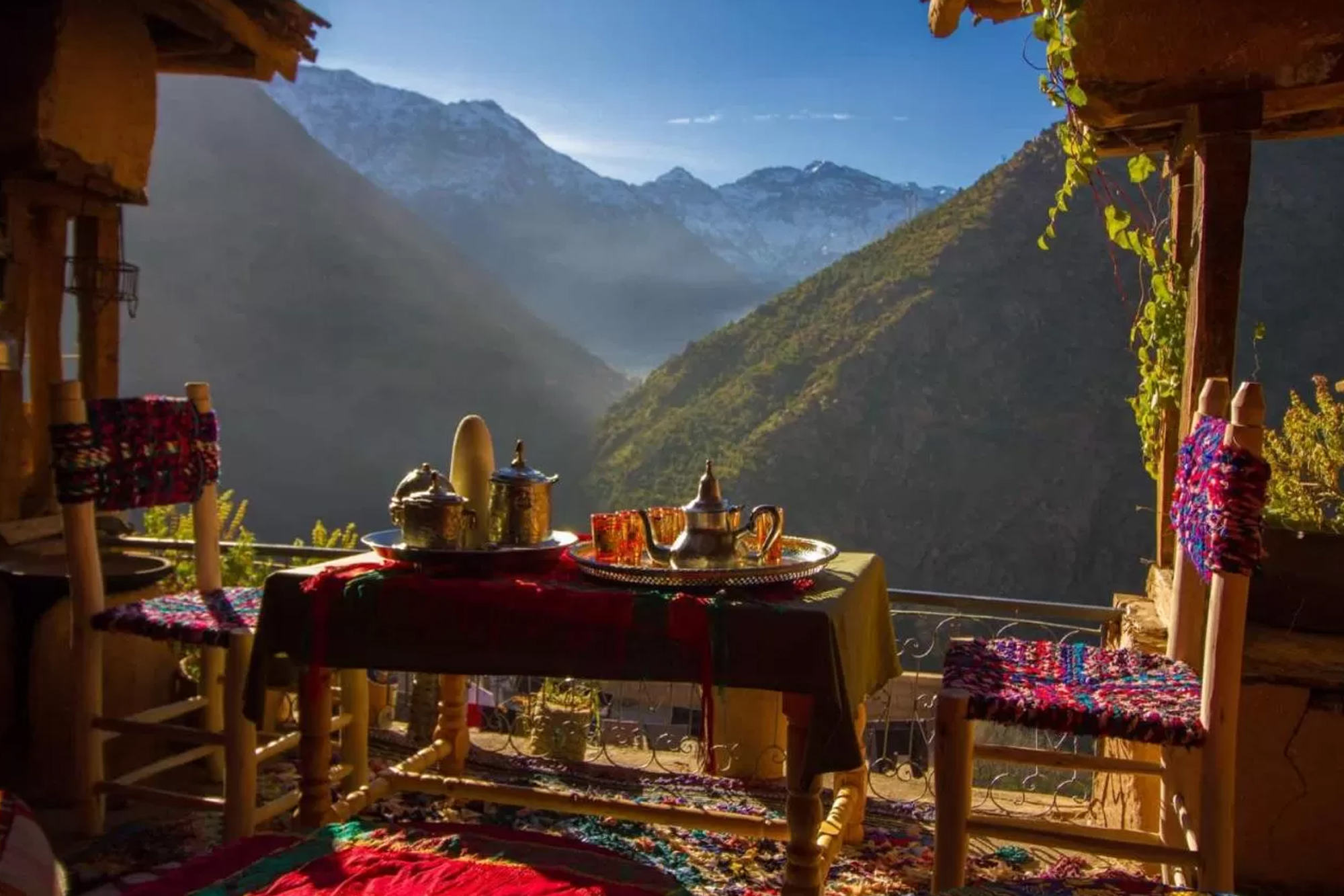 Table dressée pour le thé sous une pergola de bois, face aux sommets enneigés du Toubkal