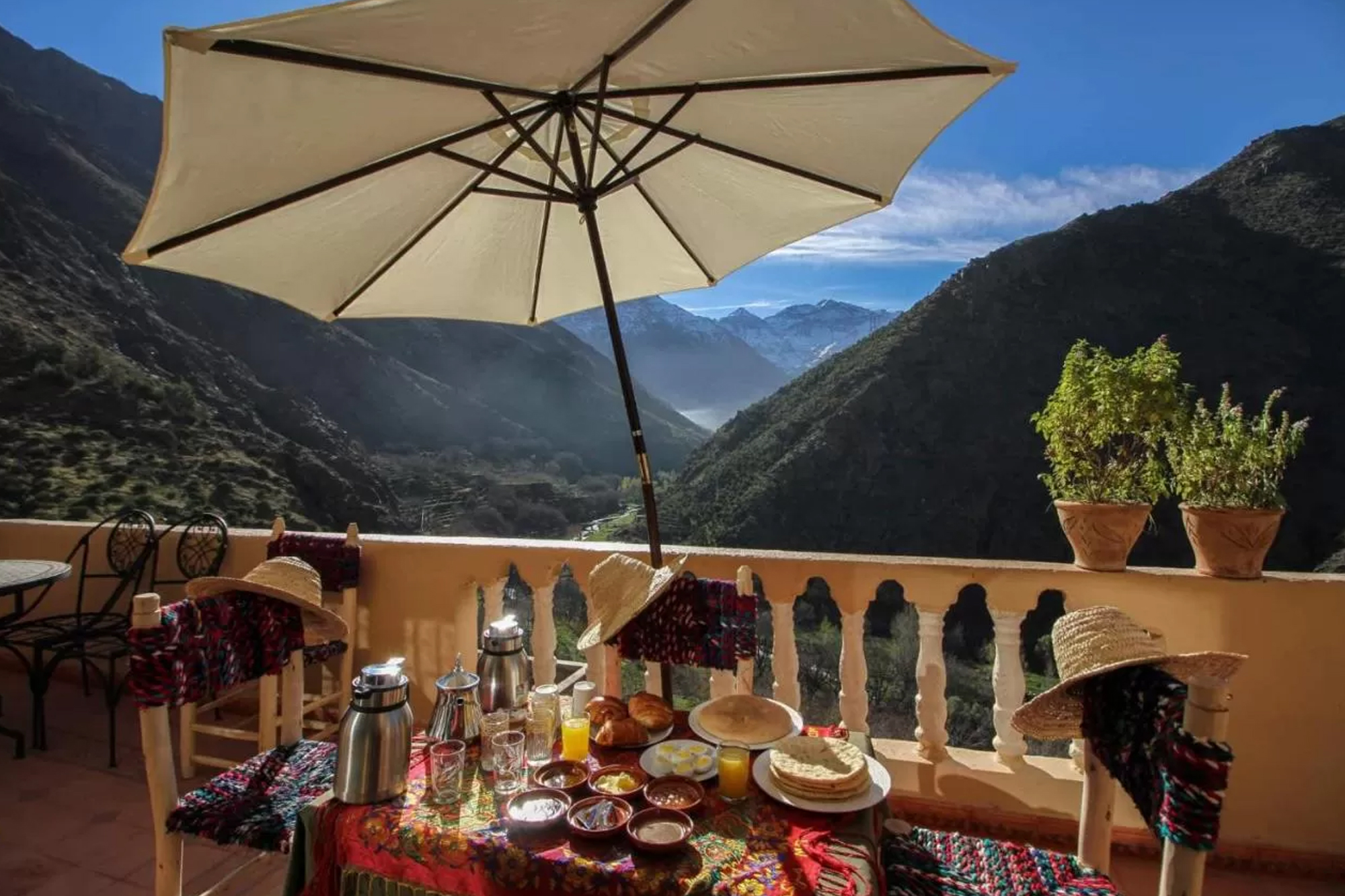 Petit-déjeuner servi sous un parasol, la vallée et les crêtes enneigées en perspective