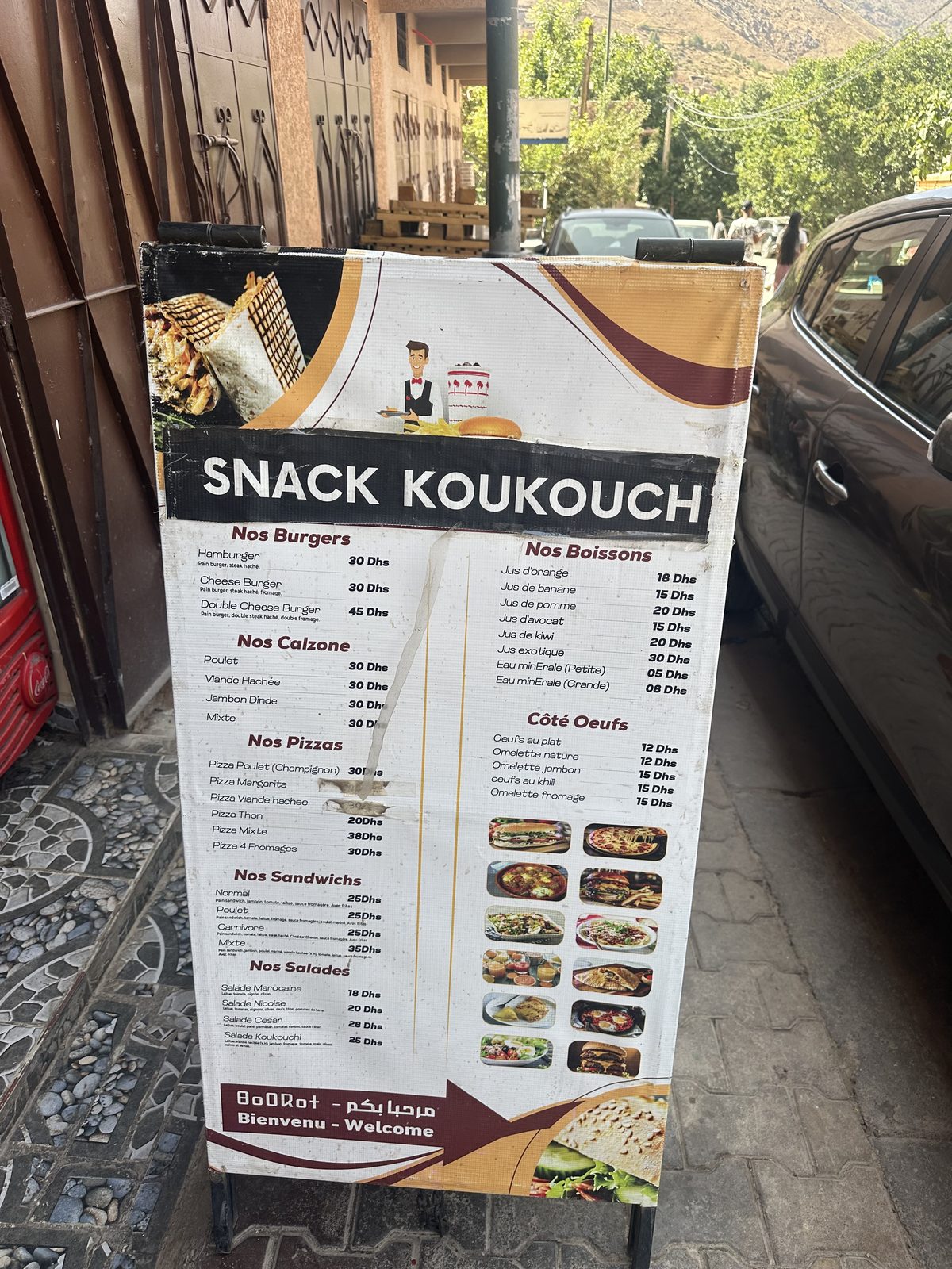 Le panneau de la carte posé devant l'entrée, burgers, calzones, pizzas, sandwichs et salades avec leurs prix